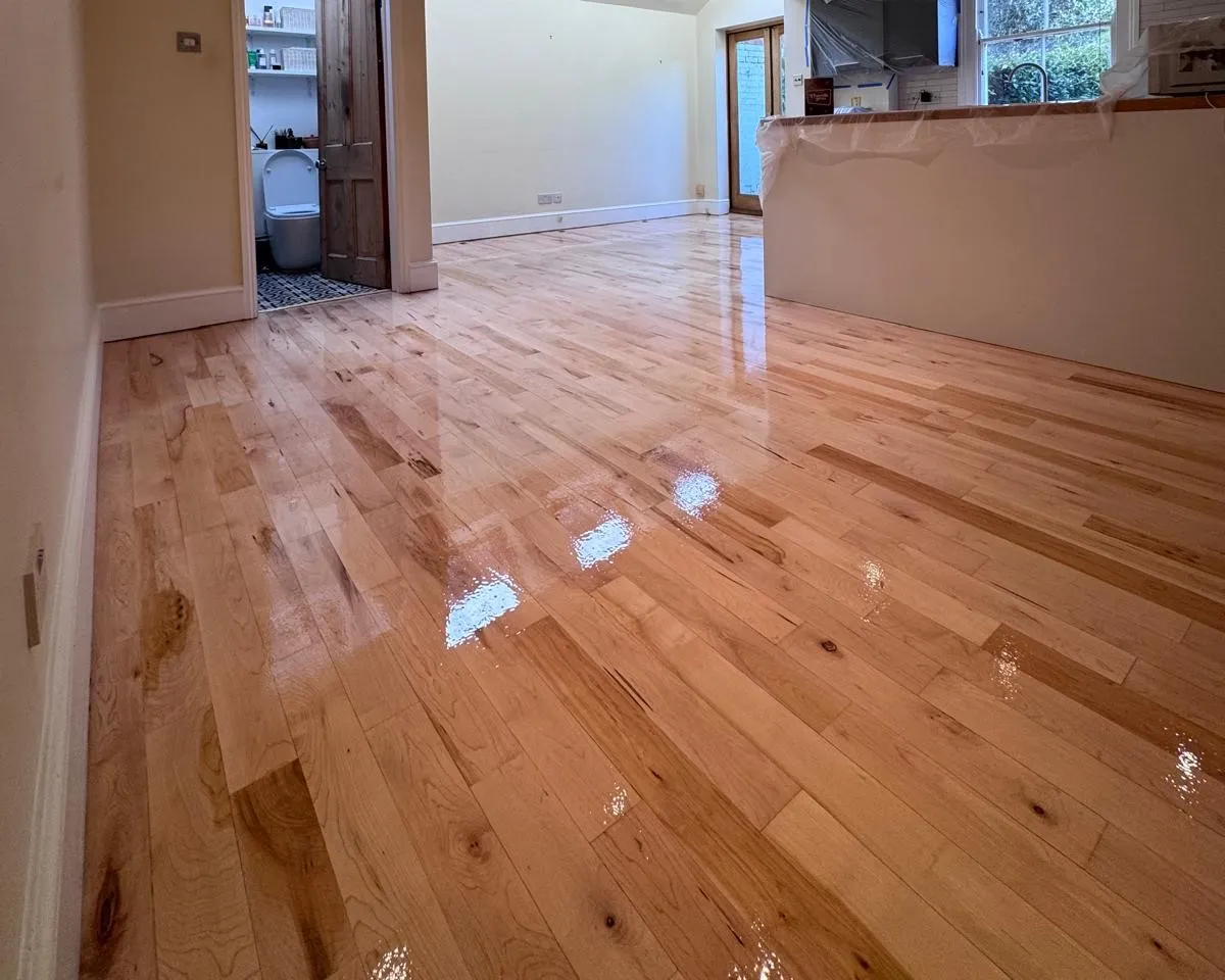 Hardwood Floor Refinishing in Southwark – light oak strip hardwood floor in an open-plan living and kitchen area, restored to a smooth, high-gloss finish.