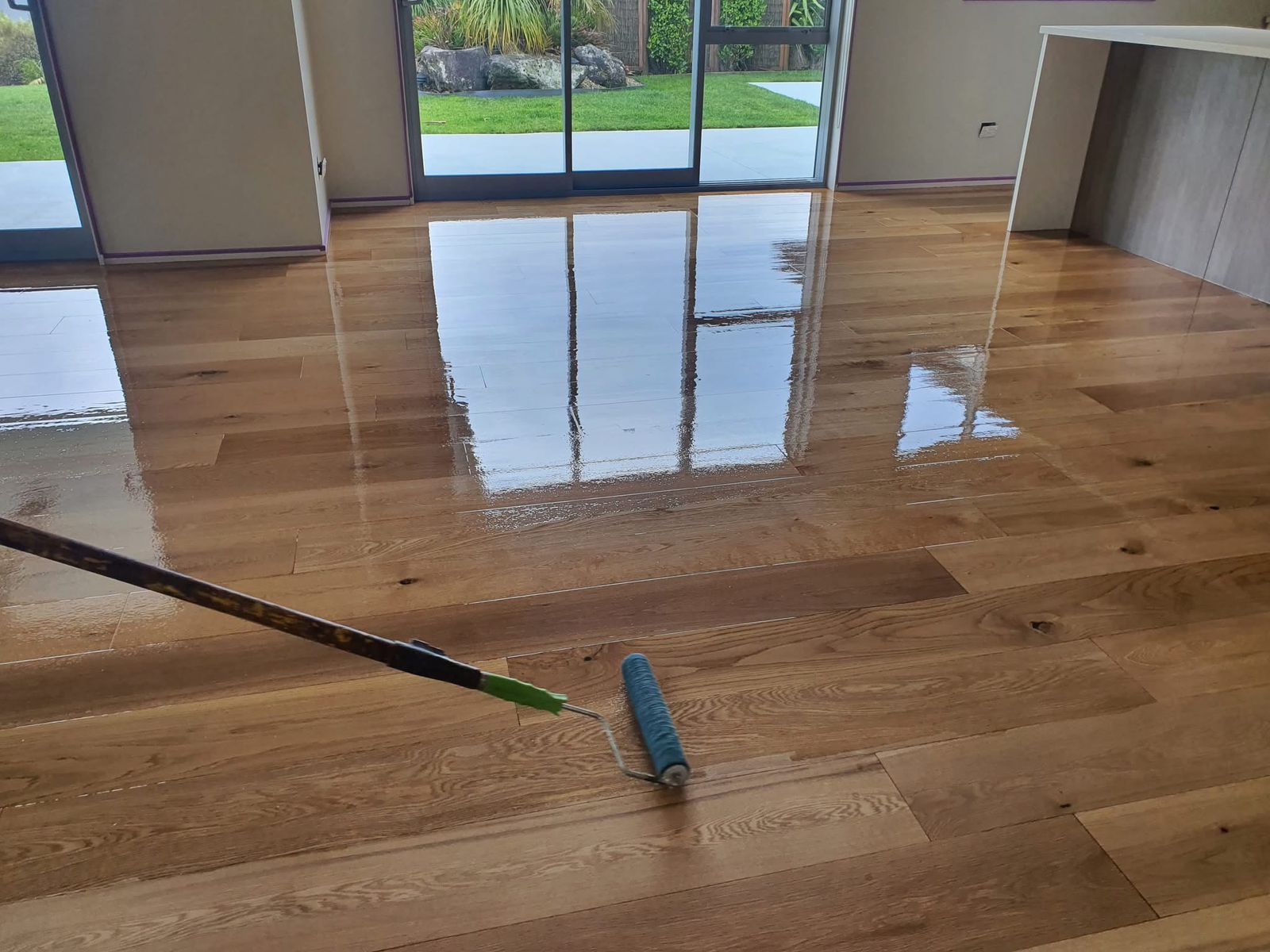 Hardwood Floor Refinishing in Southwark – solid oak plank hardwood floor in a bright living room, freshly coated with lacquer using a roller, showing a smooth, high-gloss finish.